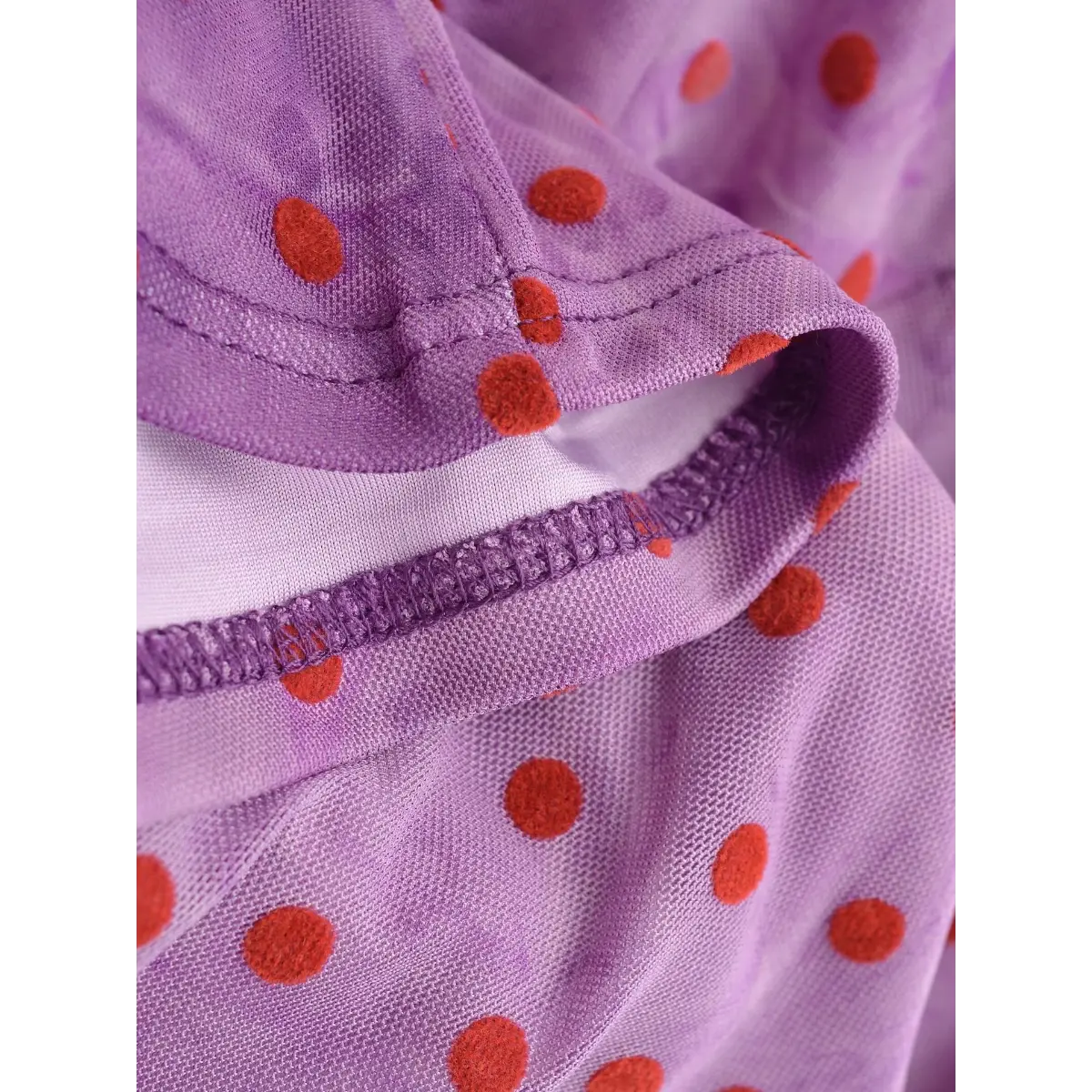 Close-up of the overlock stitching at the neckline, revealing the sheer mesh and smooth lining construction.