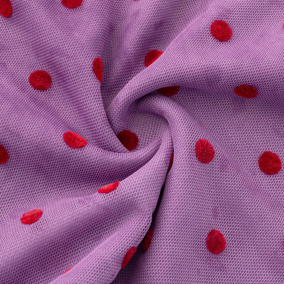 Folded view of the purple mesh fabric with red polka dots, highlighting the soft drape and flocked dot texture