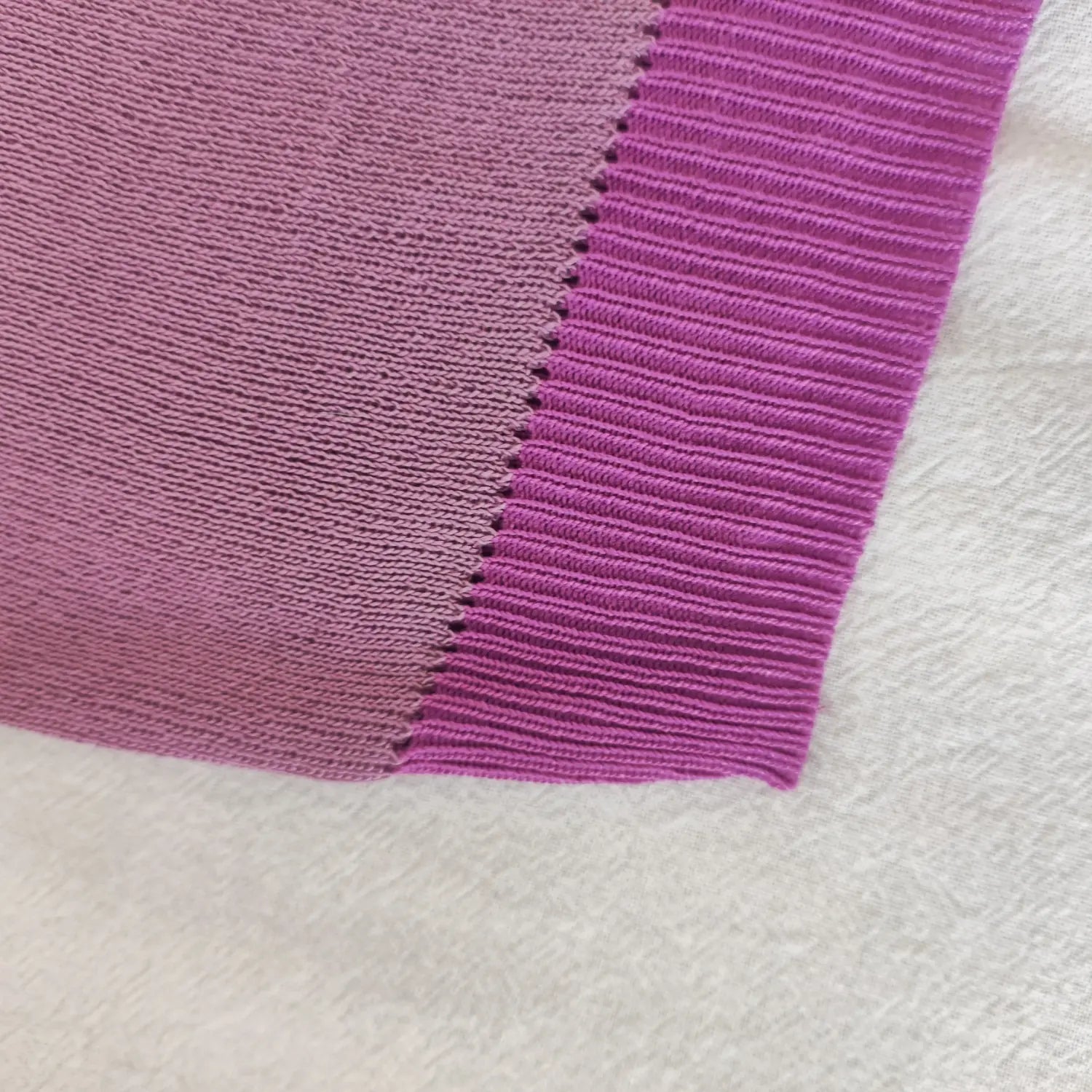 Close‑up ribbed hem band and edge stitching detail of purple knit strapless tube top