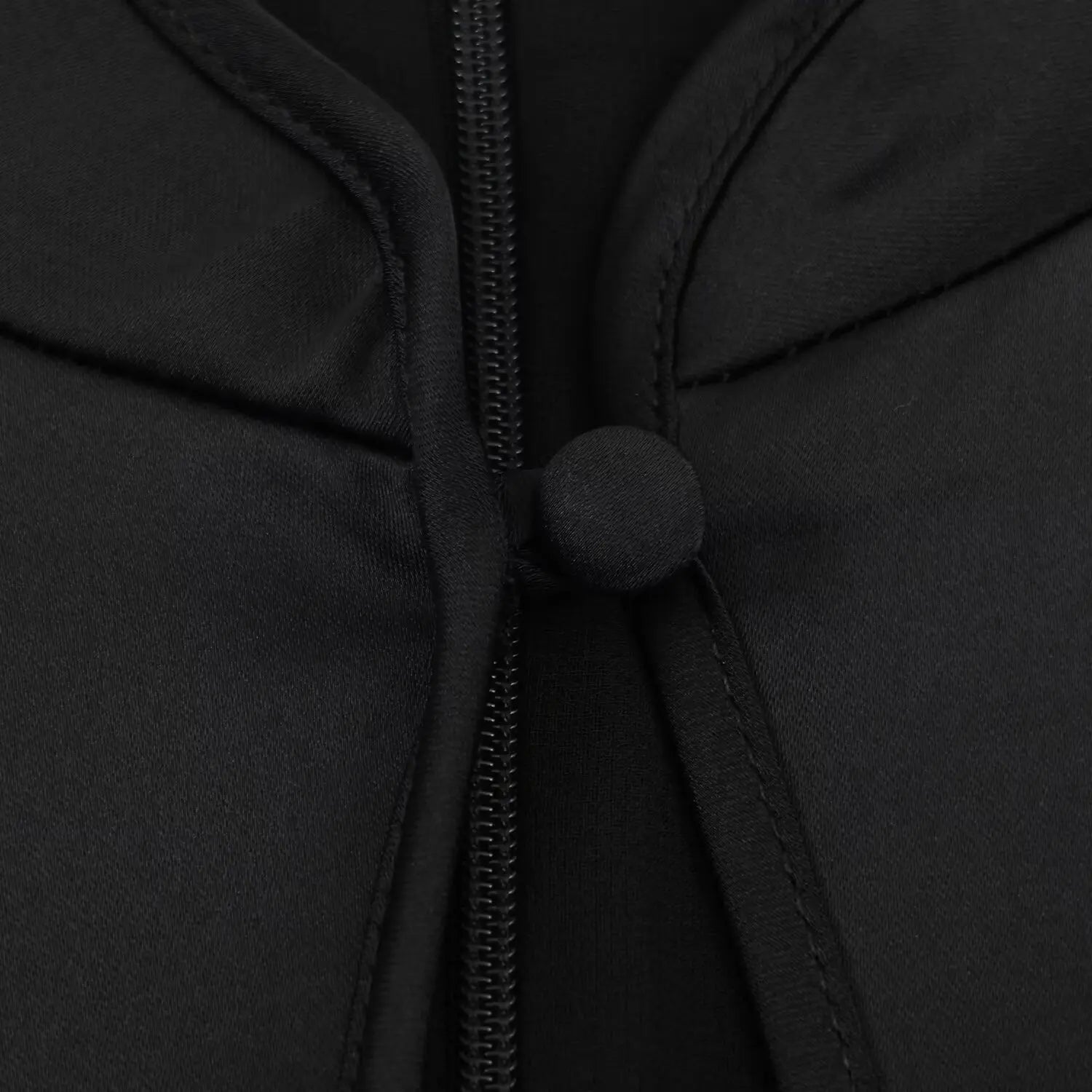 Front neck macro shot, round fabric frog button, vertical invisible zipper inside hollow cutout, smooth black satin fabric
