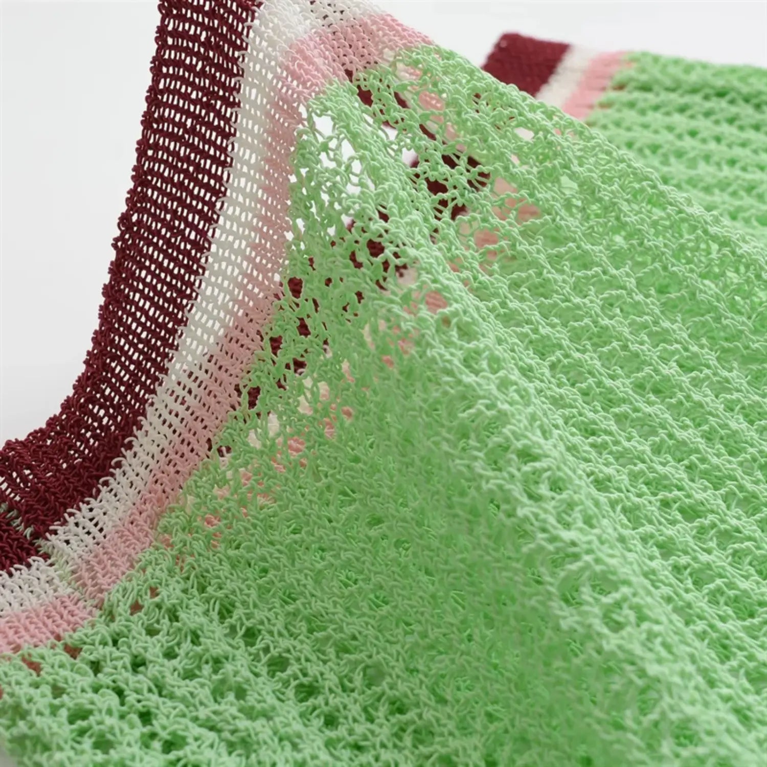 Shoulder and sleeve partial view, diagonal raglan seam, openwork mesh knit texture, soft mint green yarn structure
