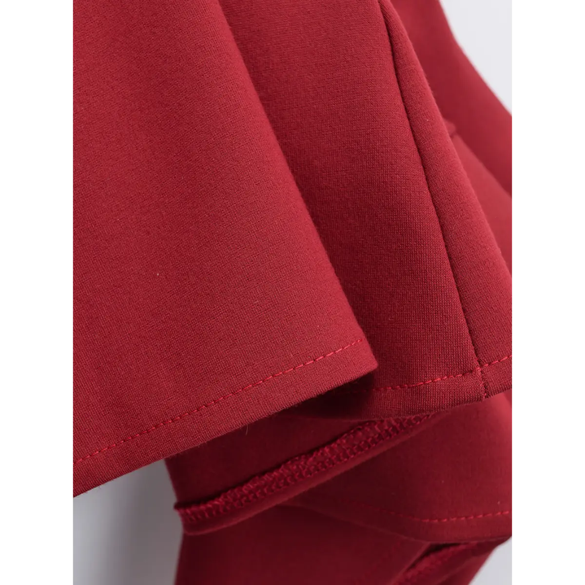 Close-up of the fabric texture and flared hem on the red cami dress