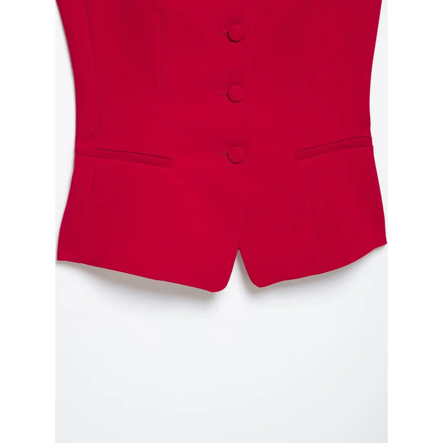 Close‑up bottom hem of red cami top, fake welt pocket details, front split hem, structured tailored suiting fabric, white background