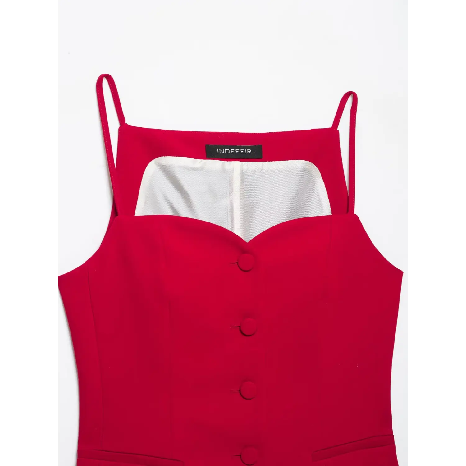 Close‑up detail of red cami top, sweetheart neckline, brand label, front fabric covered buttons, inner white lining, white background