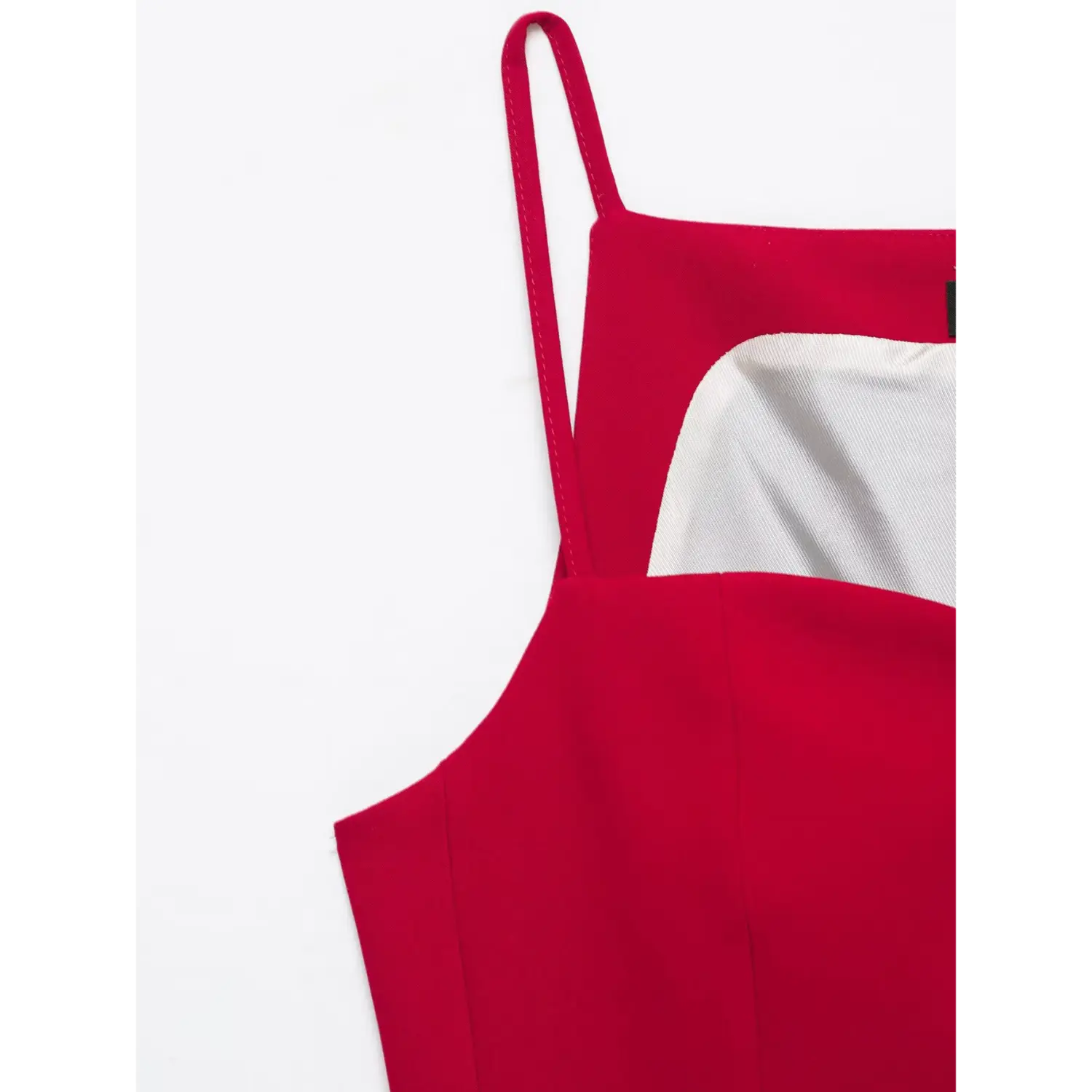 Close‑up of red cami top thin spaghetti strap, shoulder seam and inner lining detail, smooth suiting fabric, white background