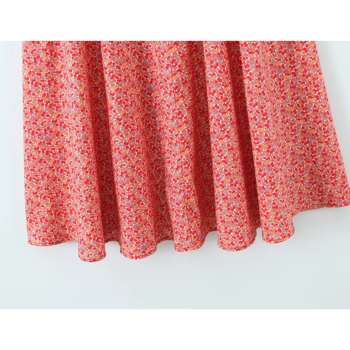 Close-up of flowy A-line skirt hem on cherry floral halter midi dress, showing gathered panel and neat finished edge.