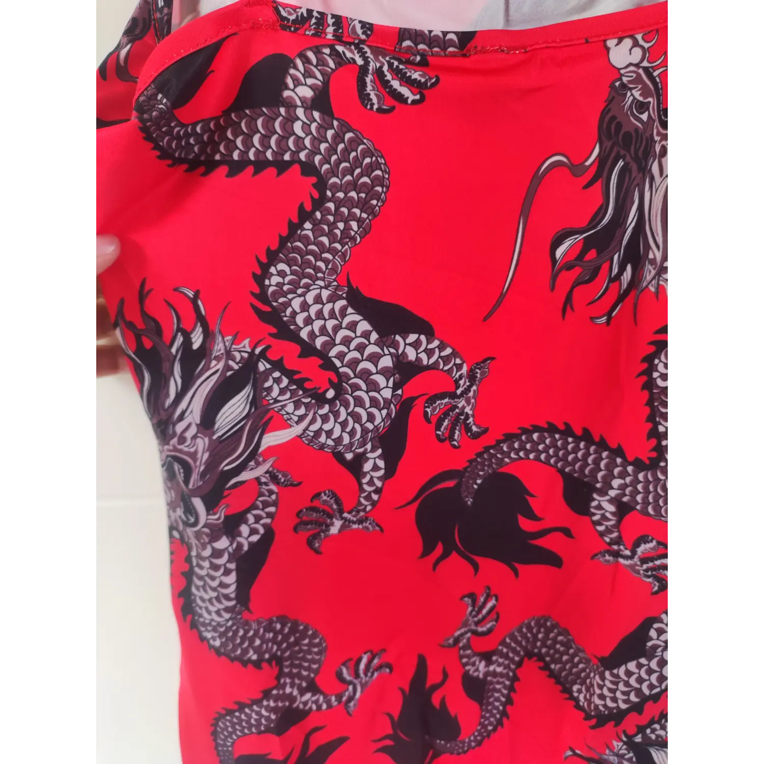 Close-up texture view, black and grey traditional dragon pattern on red dress fabric
