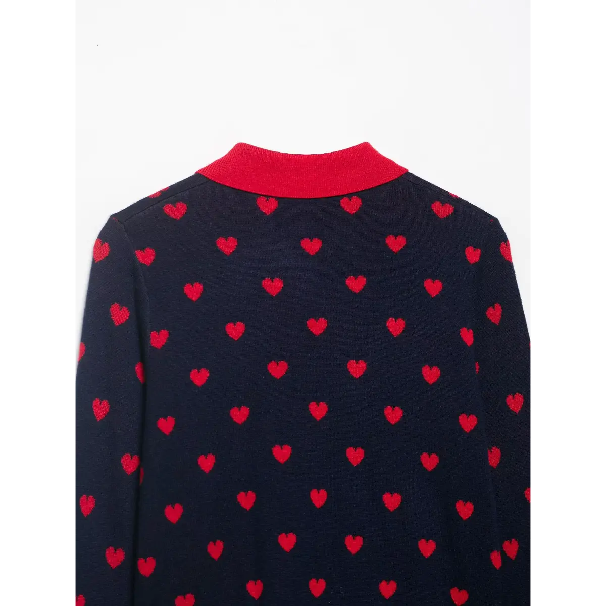 Close-up of the red collar on a navy and red heart-patterned knit cardigan, showing the heart pattern on the back.