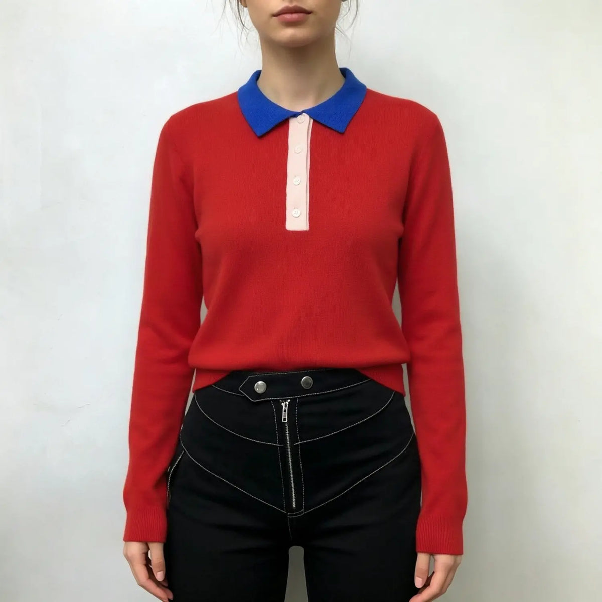 Model wearing red color block knit polo top with blue collar, paired with black pants
