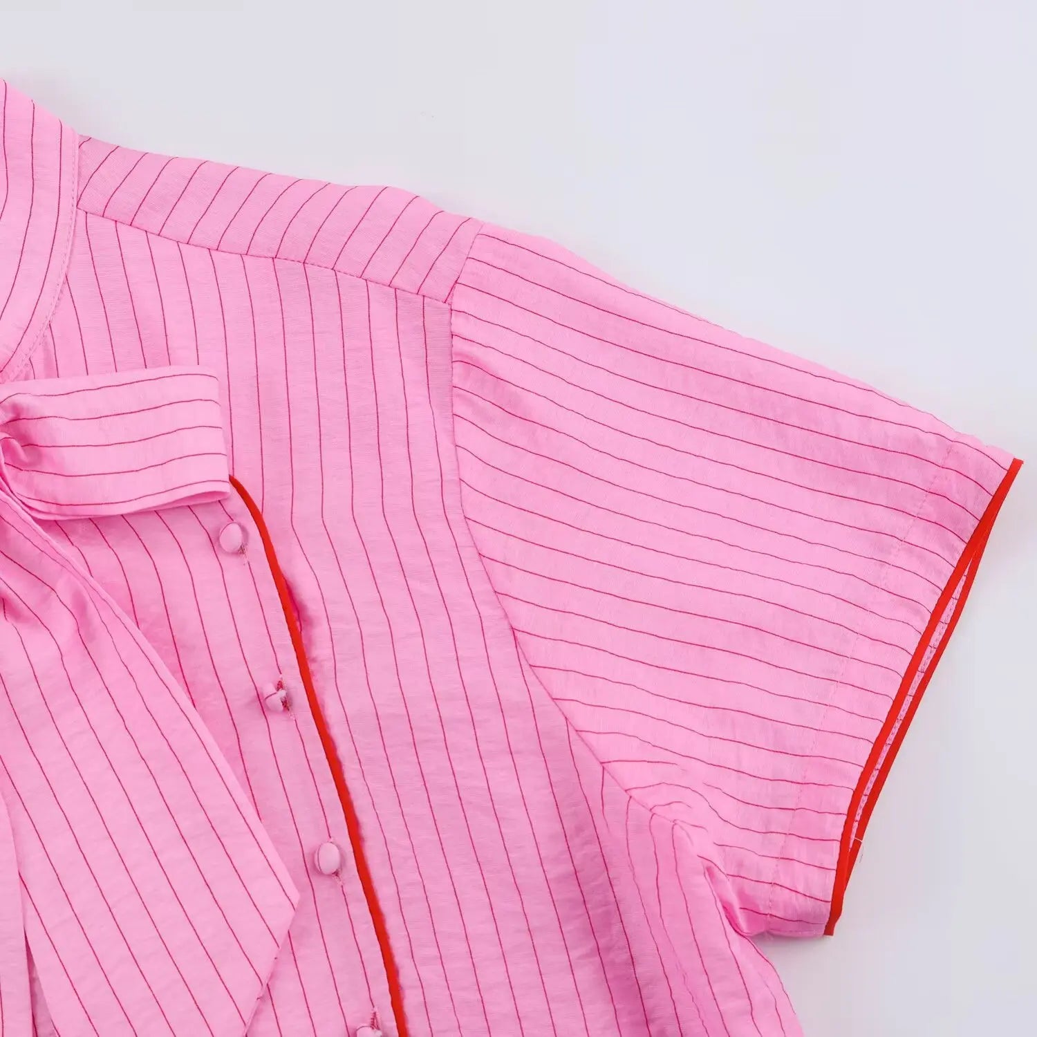 Detail shot red piping trim along placket edge and short sleeve hem