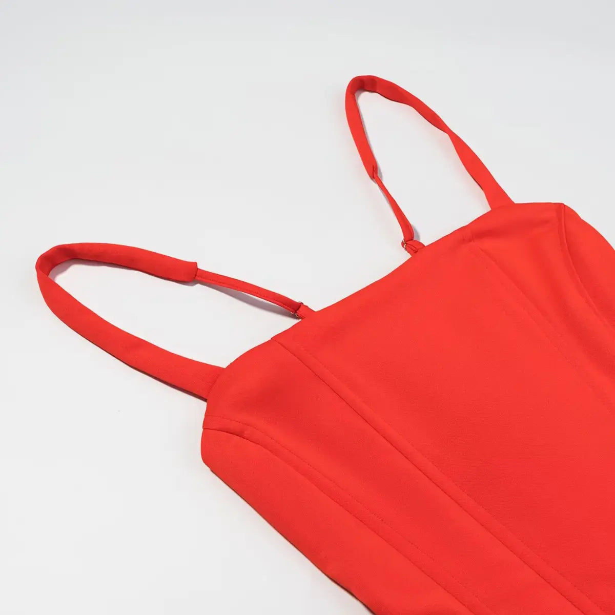 Close-up of the front bodice on the red corset-style mini dress, featuring vertical boning seams and adjustable straps