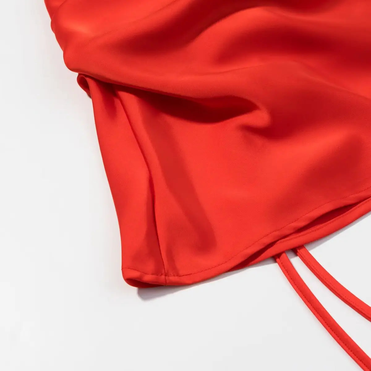 Close-up of the skirt hem on the red mini dress, showing the clean stitching and smooth fabric finish