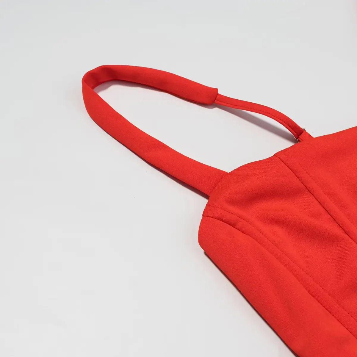Close-up of the adjustable spaghetti strap on the red corset-style mini dress, showing the structured seam and smooth fabric