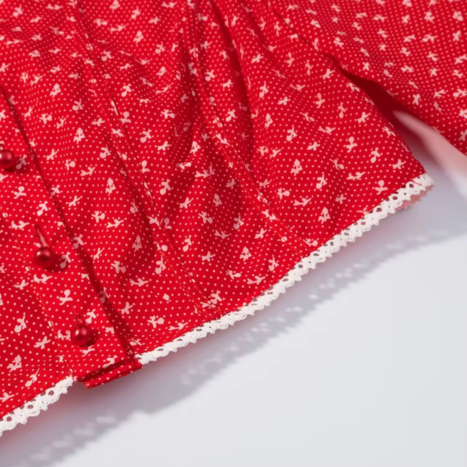 Macro shot of white lace trim hem on red ditsy floral cropped blouse