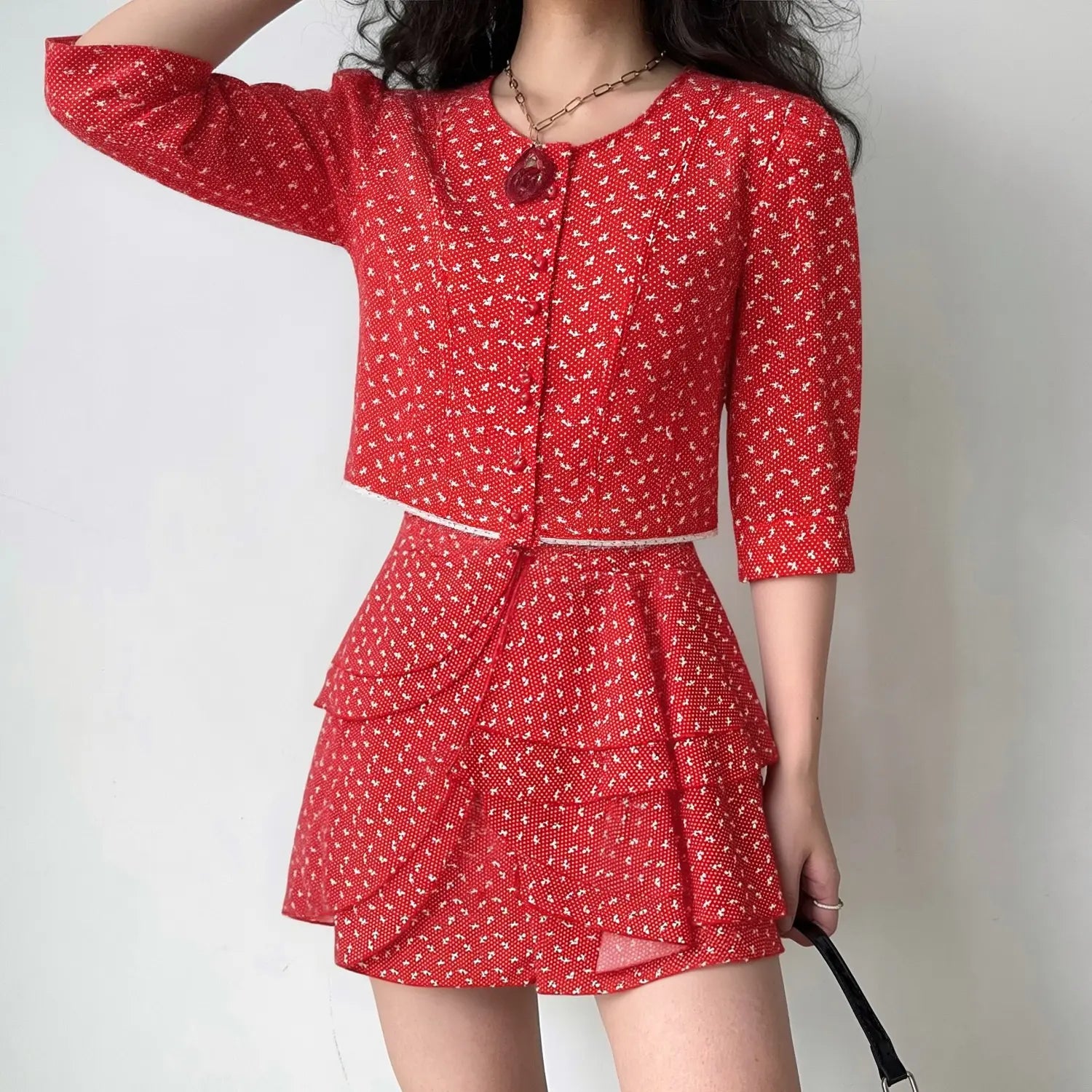Model wearing red ditsy floral co‑ord set, cropped puff sleeve top and tiered ruffle mini skirt