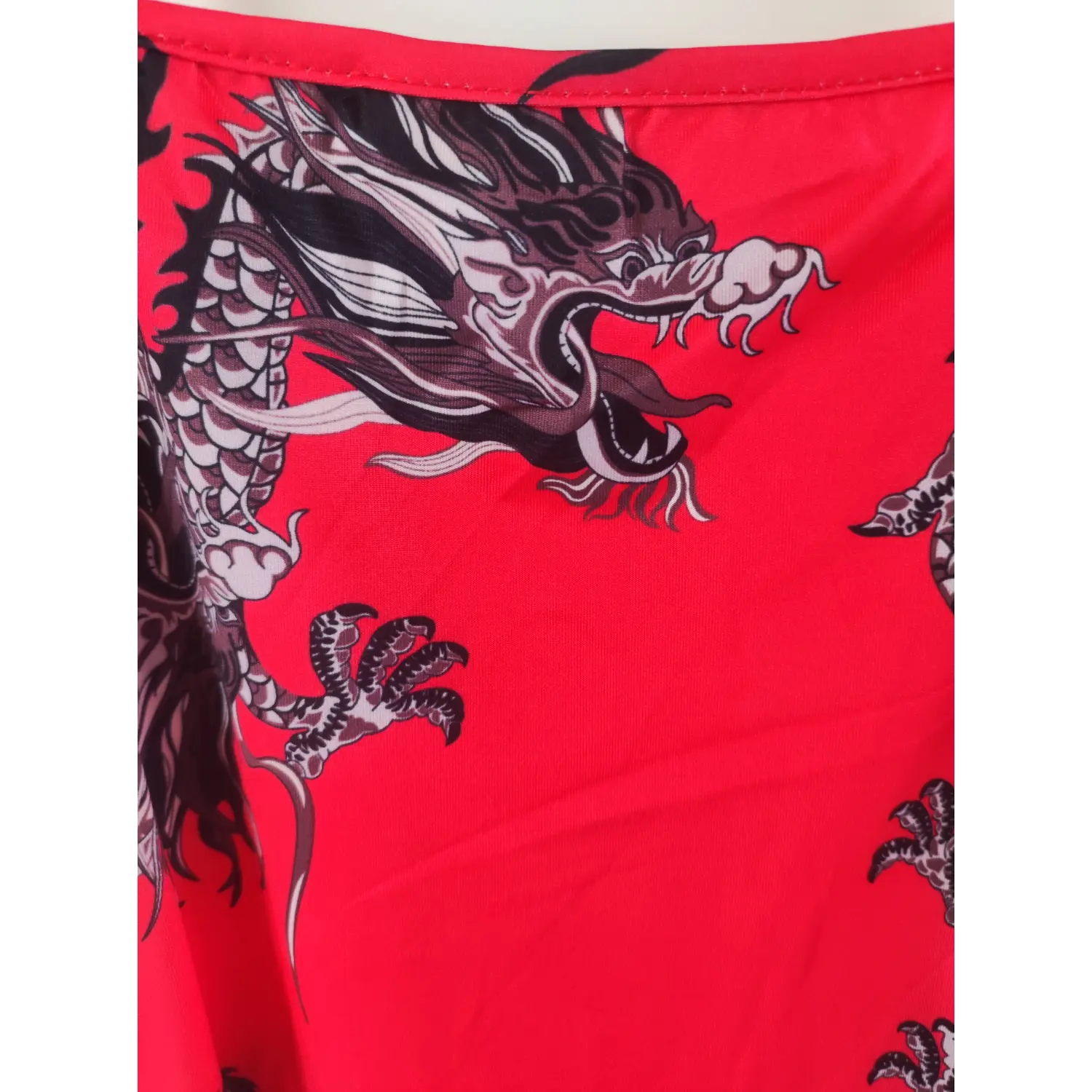 Close-up fabric shot, bright red spaghetti strap mini dress with vintage black oriental dragon print