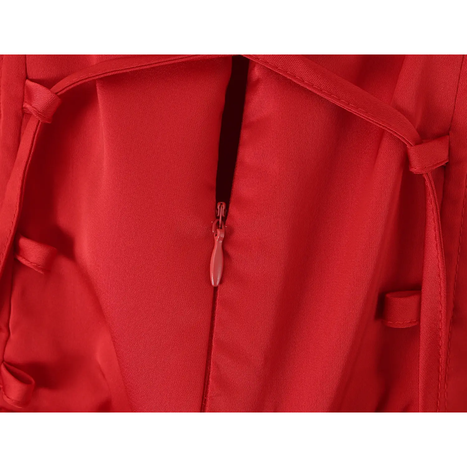 Extreme close up of matching red hidden zipper pull tab on corset lace up back satin dress