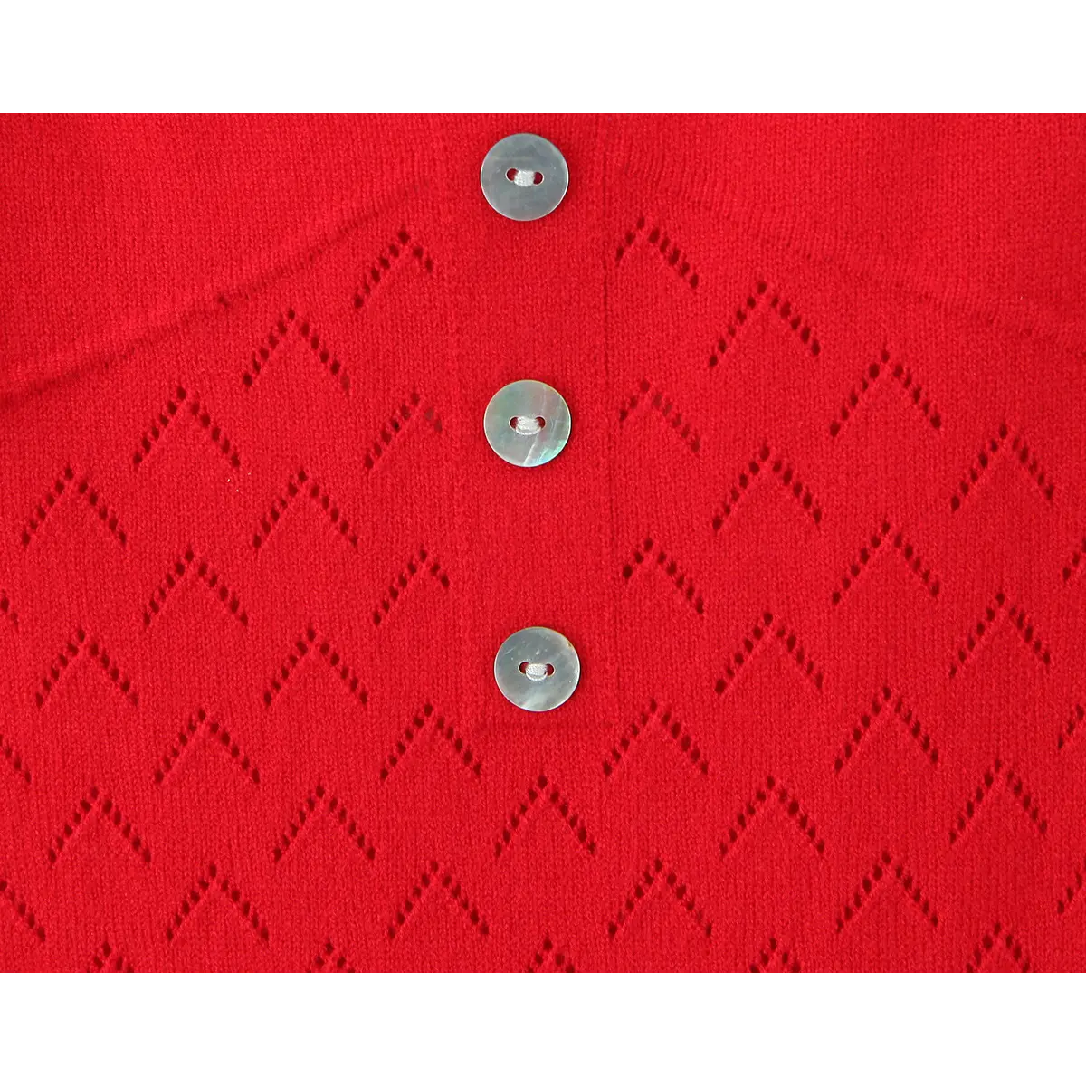 Close detail of natural shell round buttons on red hollow knit halter dress bust placket.