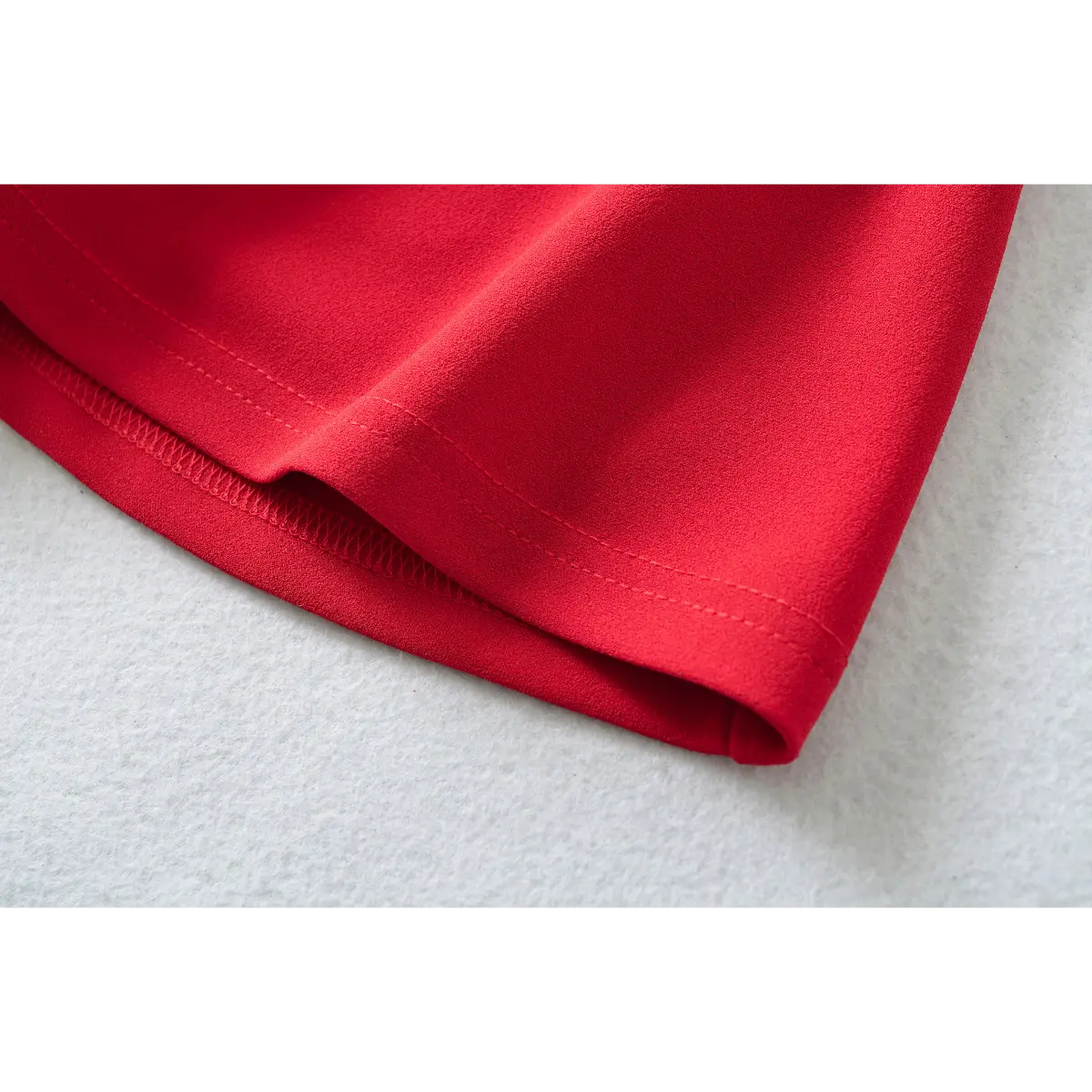Close-up of the double-stitched hem on a red fit-and-flare mini dress.