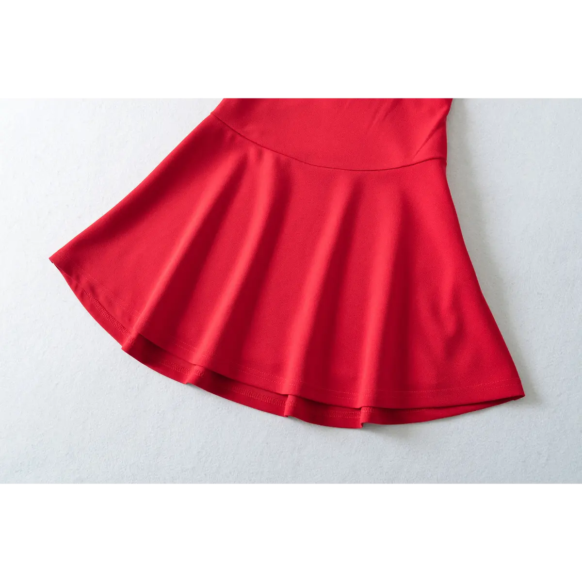 Close-up of the flared skirt and pleats on a red fit-and-flare mini dress.