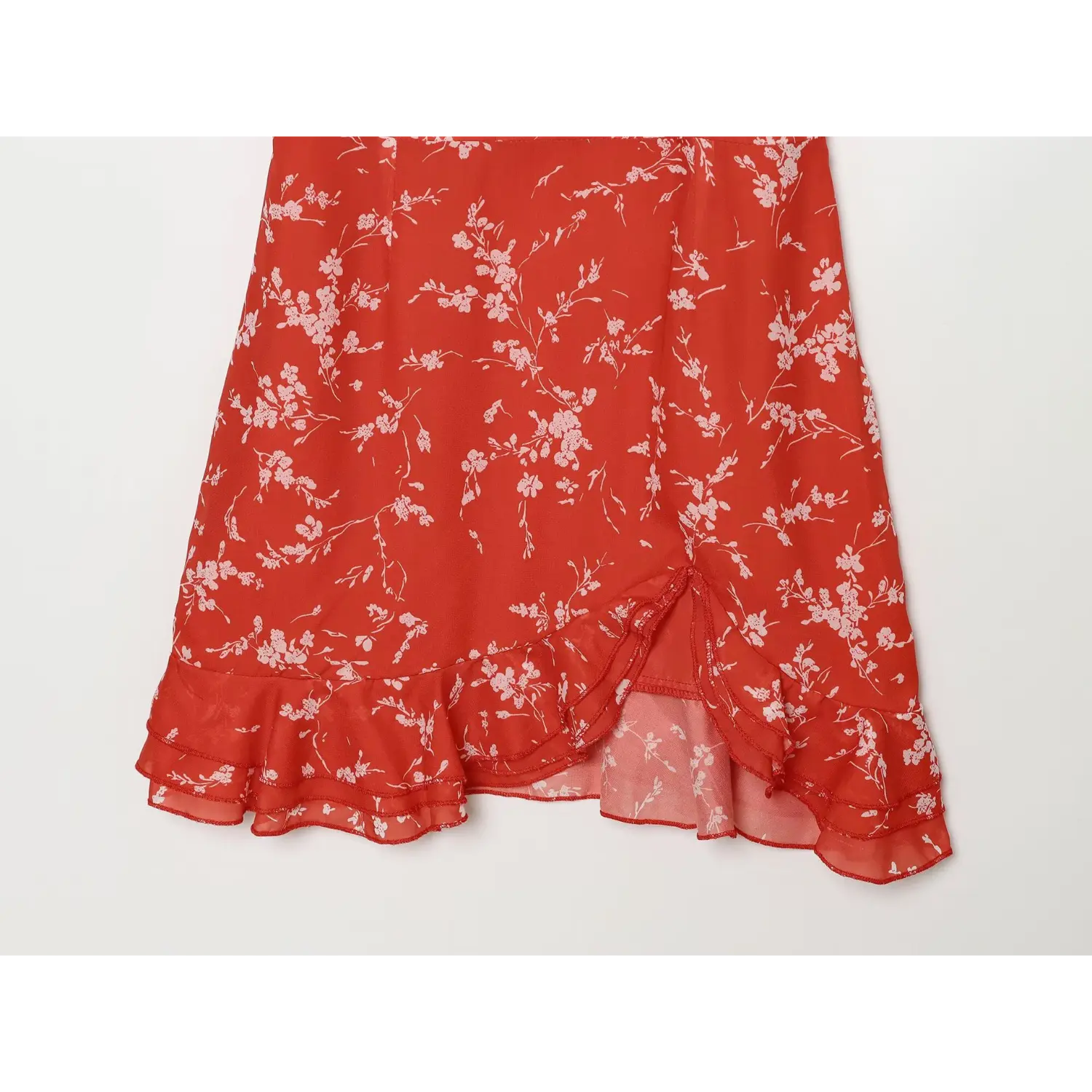 Detail shot of front skirt slit and layered ruffled hem on red floral chiffon dress