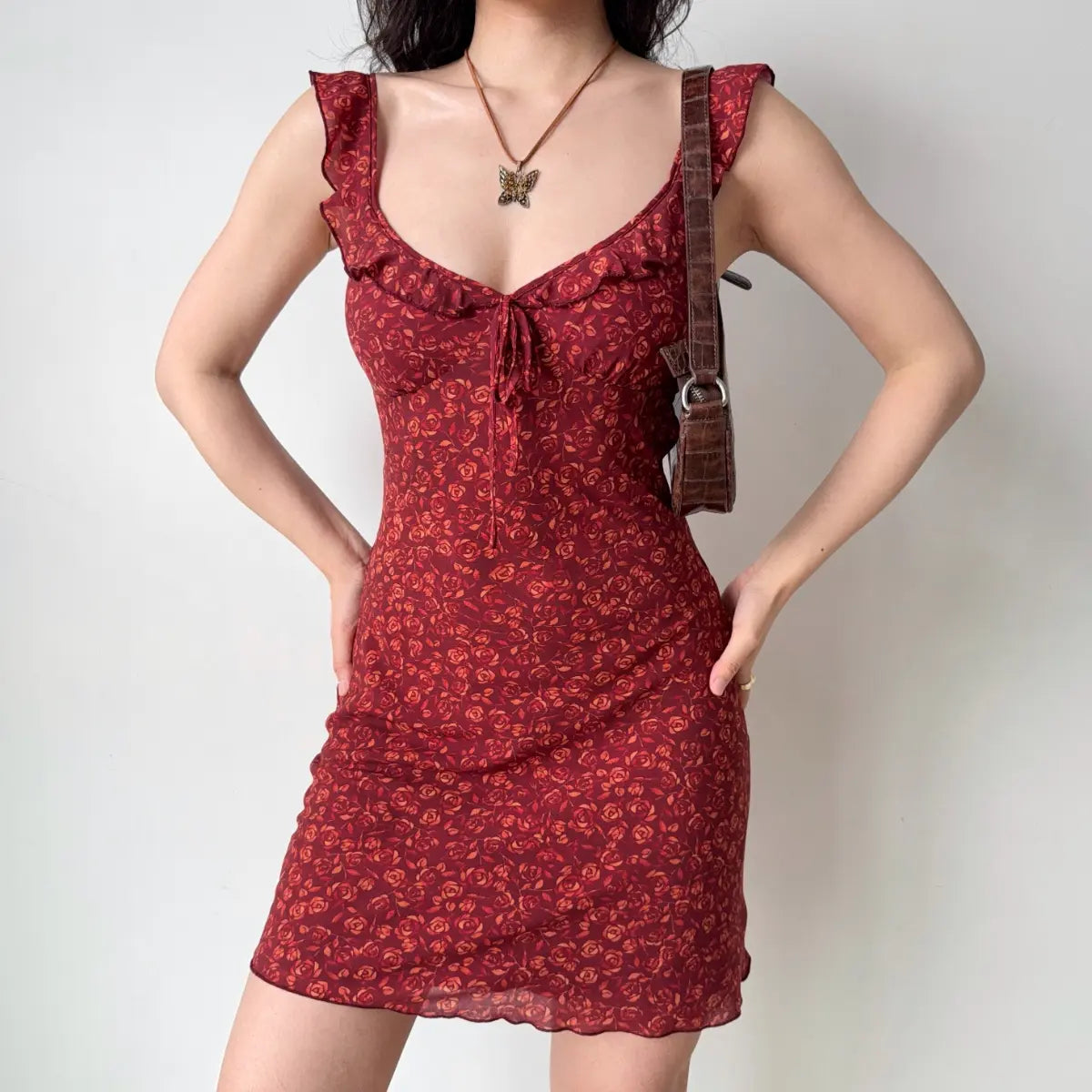 The red rose print dress styled with a brown crocodile-pattern shoulder bag.