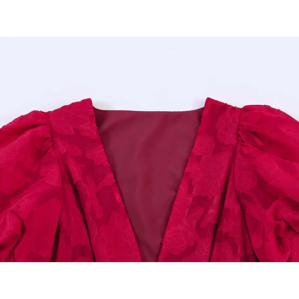 Close-up of the deep V-neckline and puff sleeves on a red floral appliqu peplum top, showing the inner lining.