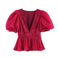 Full front view of a red floral appliqu peplum top with puff sleeves, deep V-neck, and gathered waist.