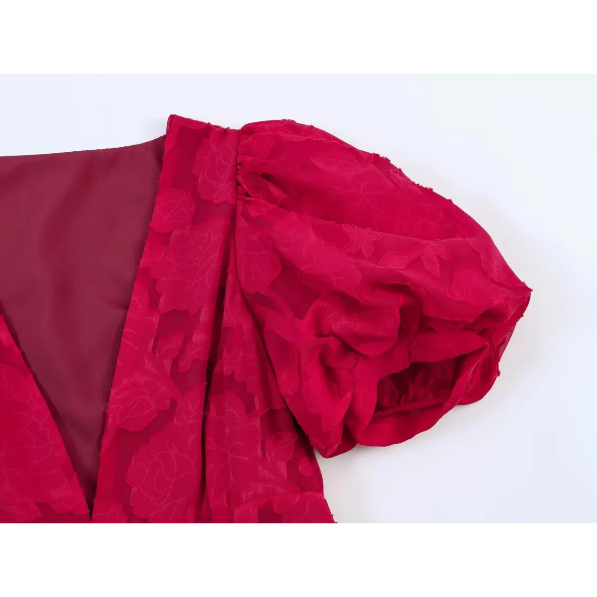 Close-up of the puff sleeve shoulder seam and gathered fabric on a red floral appliqu peplum top.