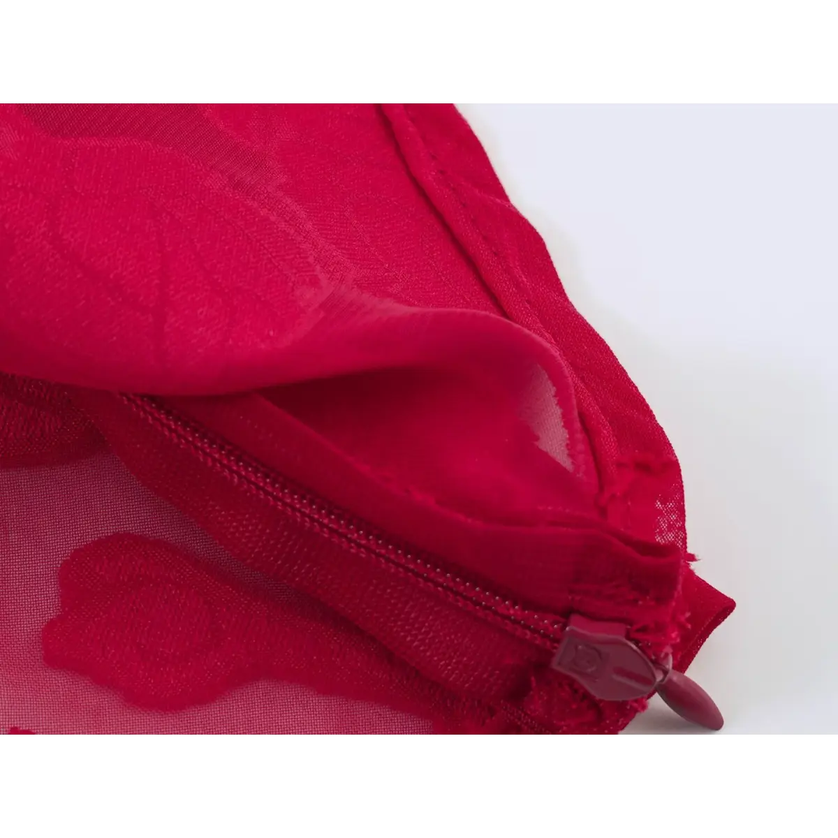 Close-up of the side zipper and semi-sheer floral appliqu fabric on a red peplum top.