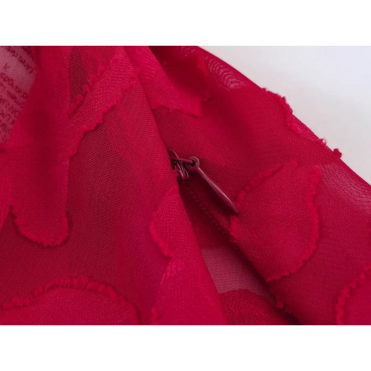 Close-up of the side zipper closure on a red floral appliqu peplum top.