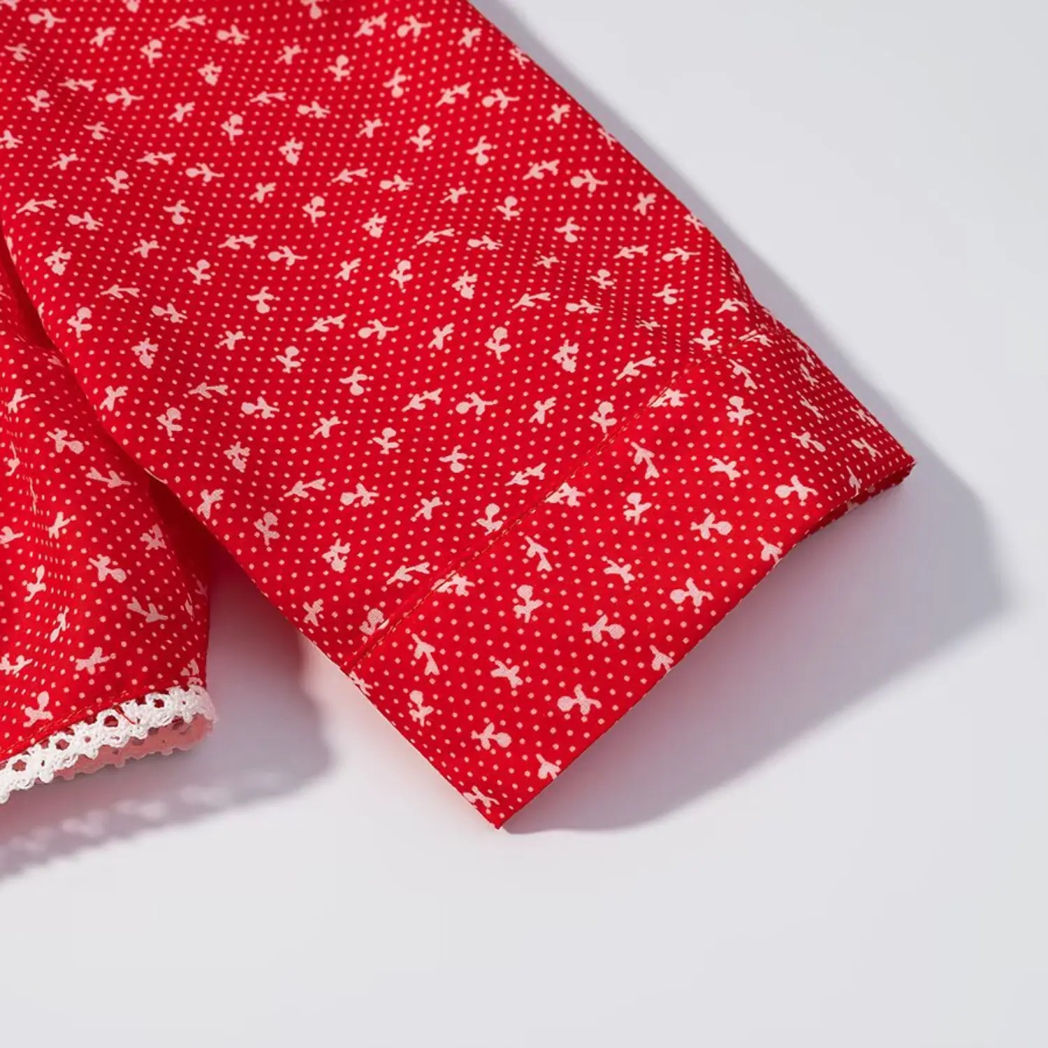 Close‑up of elbow sleeve cuff fabric detail on red ditsy floral cropped top