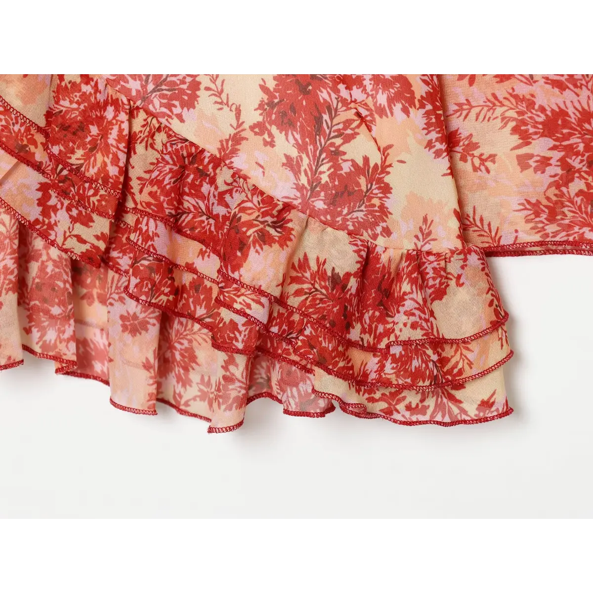 Close-up of the layered ruffled hem on the red floral wrap dress