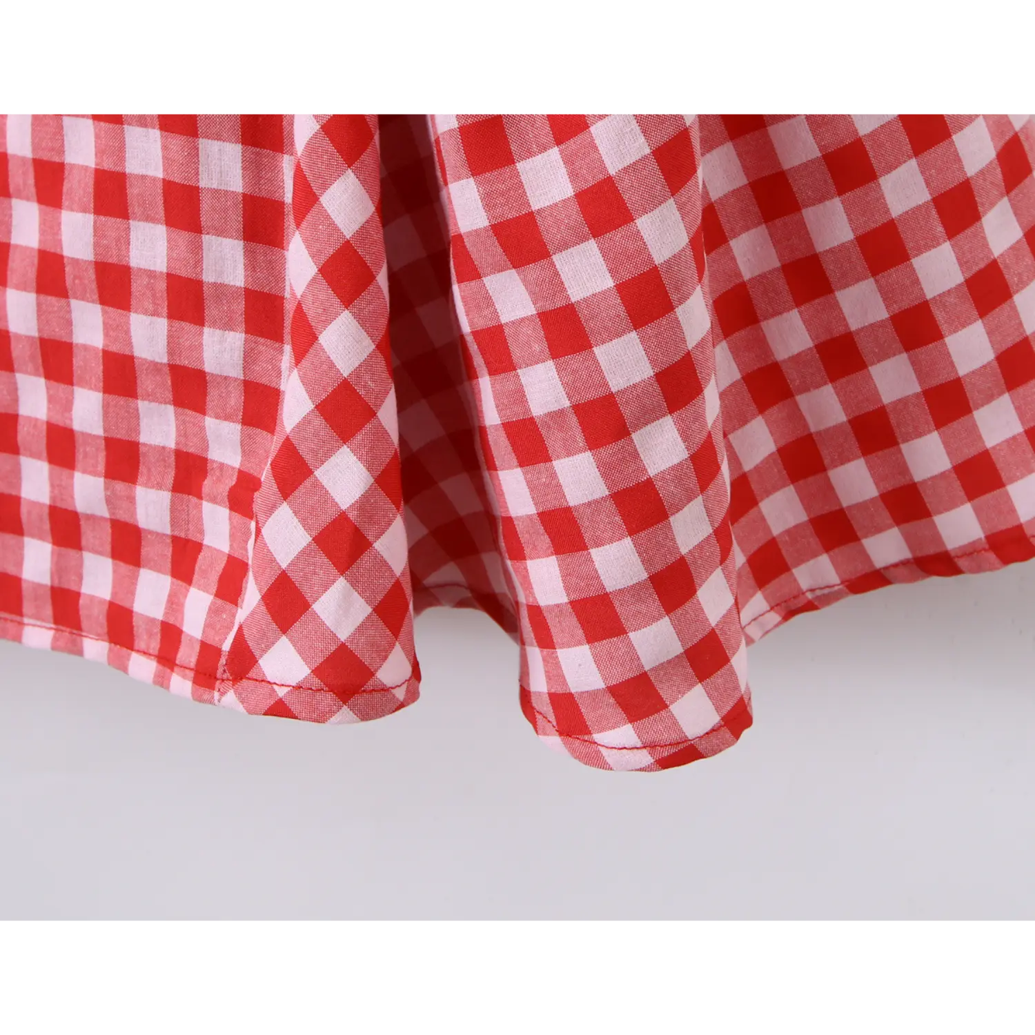 Close‑up hem stitching detail red white gingham sleeveless mini dress flared skirt edge