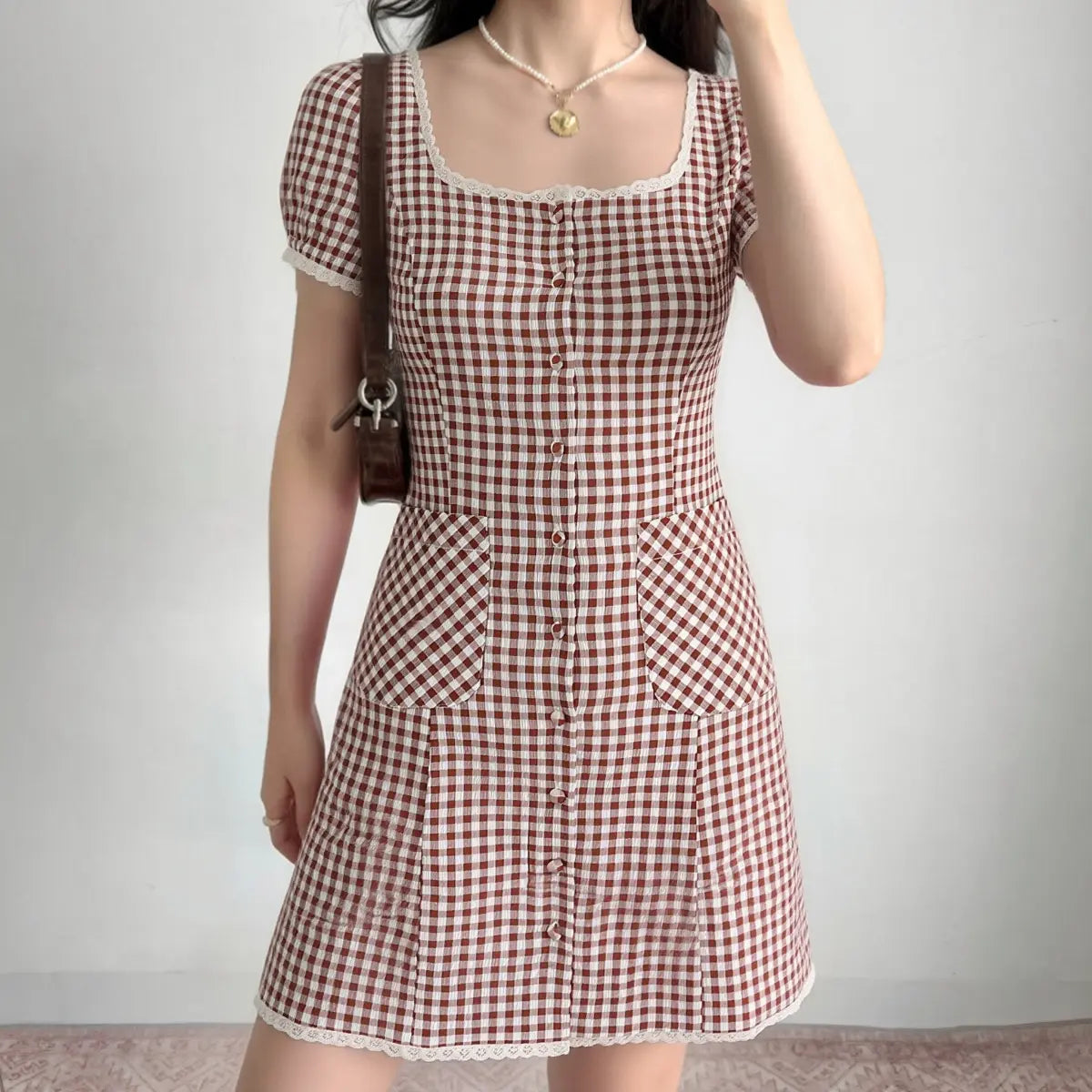Woman wearing red gingham square-neck mini dress with lace trim, full front view