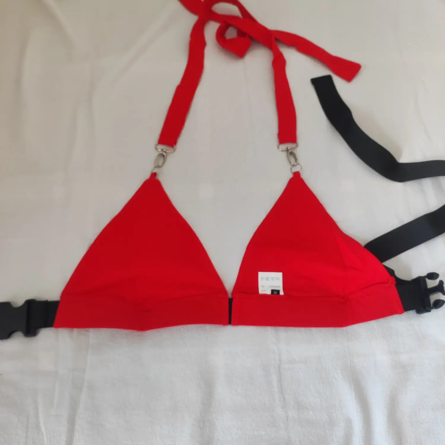 Flat lay back view red halter triangle crop top, inner clothing label and adjustable hardware displayed