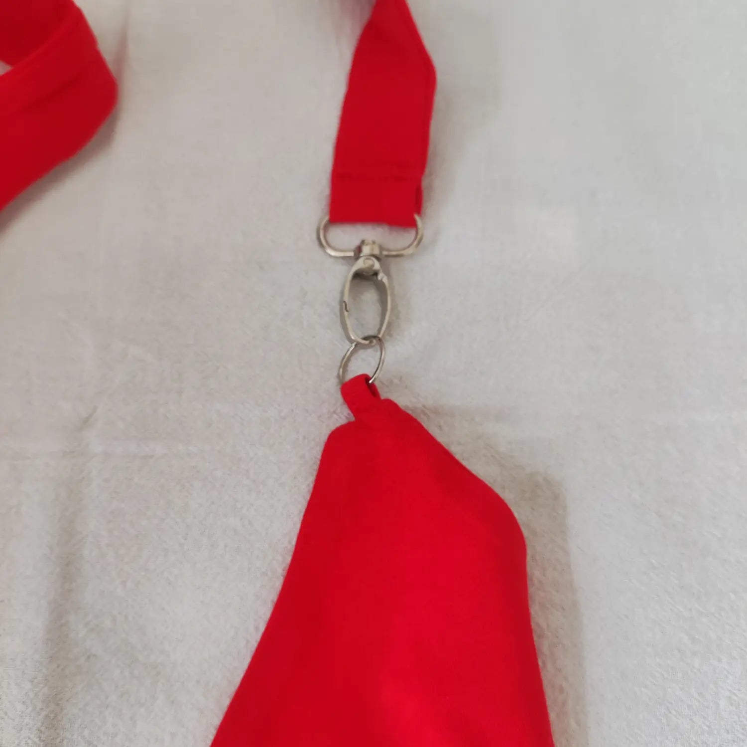 Close‑up of metal swivel clasp and ring strap detail on red halter neck triangle crop top