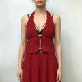Female model wearing red two‑piece outfit, deep v halter ruched crop top and tiered ruffle maxi skirt, plain light studio background