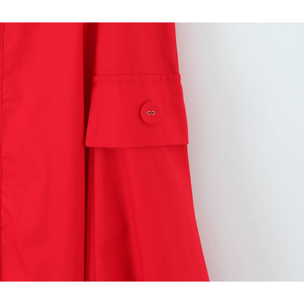 Close-up of the decorative pocket on a bright red halter maxi dress, featuring a matching red button.