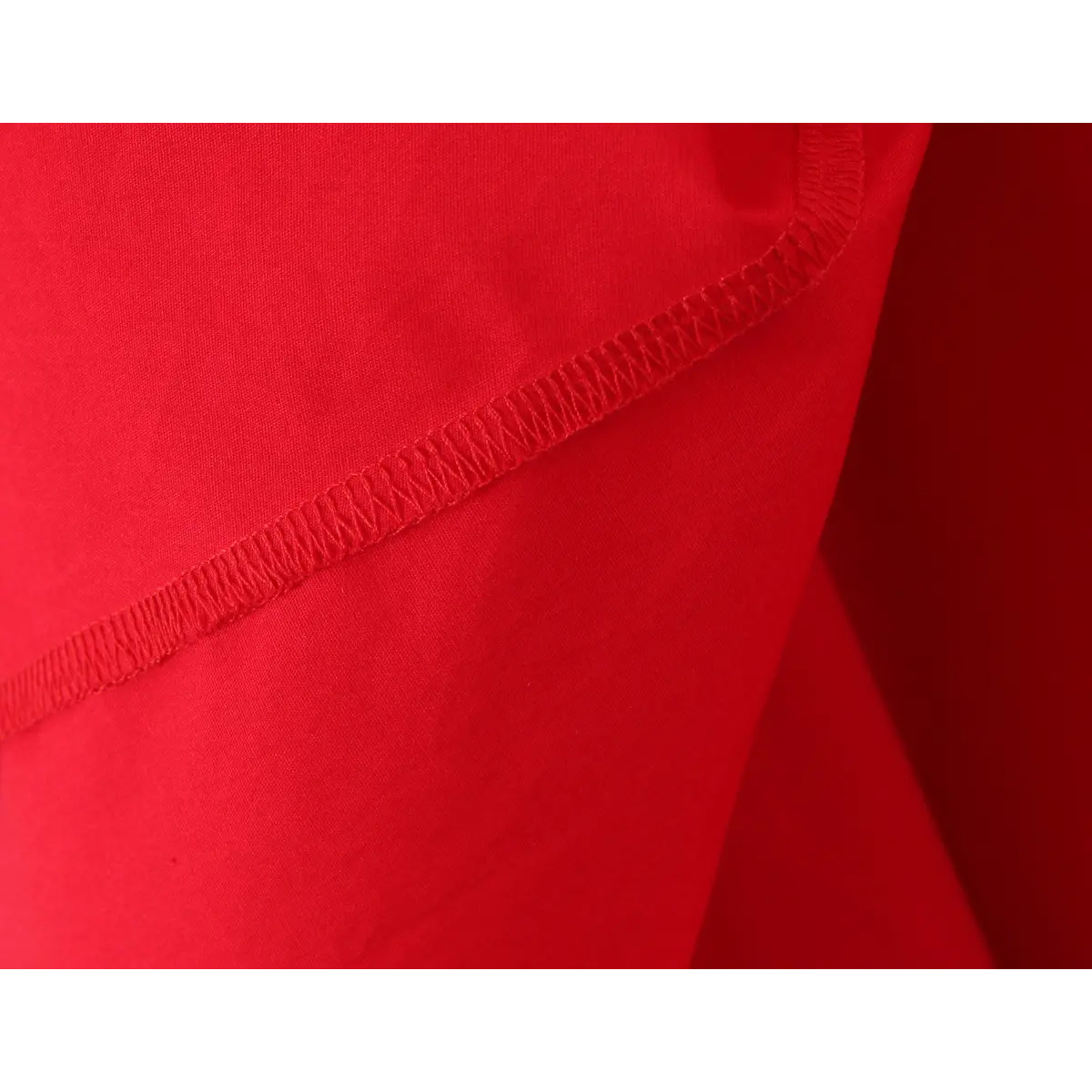 Close-up of the elasticated seam on a bright red halter maxi dress, showing the stretch stitch detail.