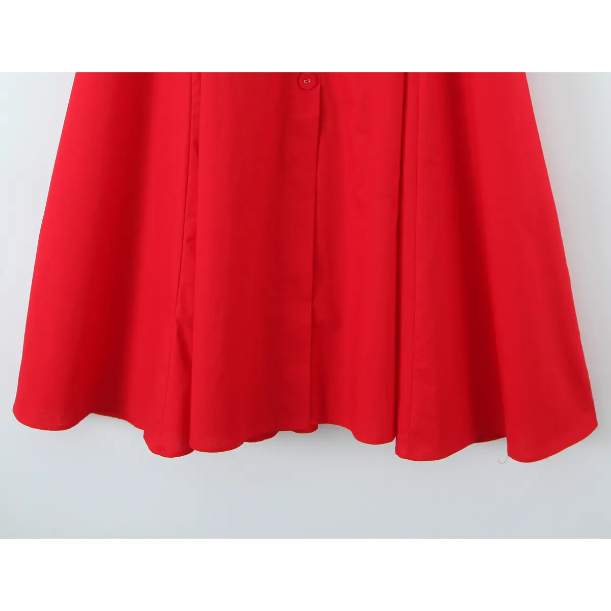  Close-up of the front placket on a bright red halter maxi dress, featuring matching red buttons and gathered skirt panels.