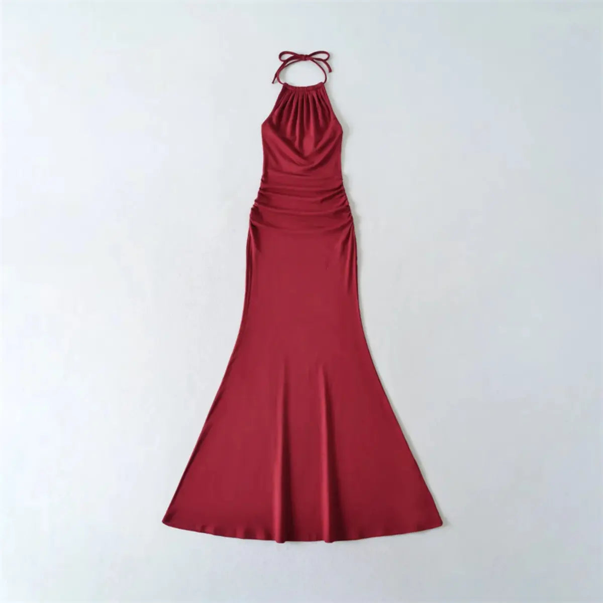 Flat lay view of a red halter-neck mermaid maxi dress, showing the full form-fitting silhouette and tied halter straps.