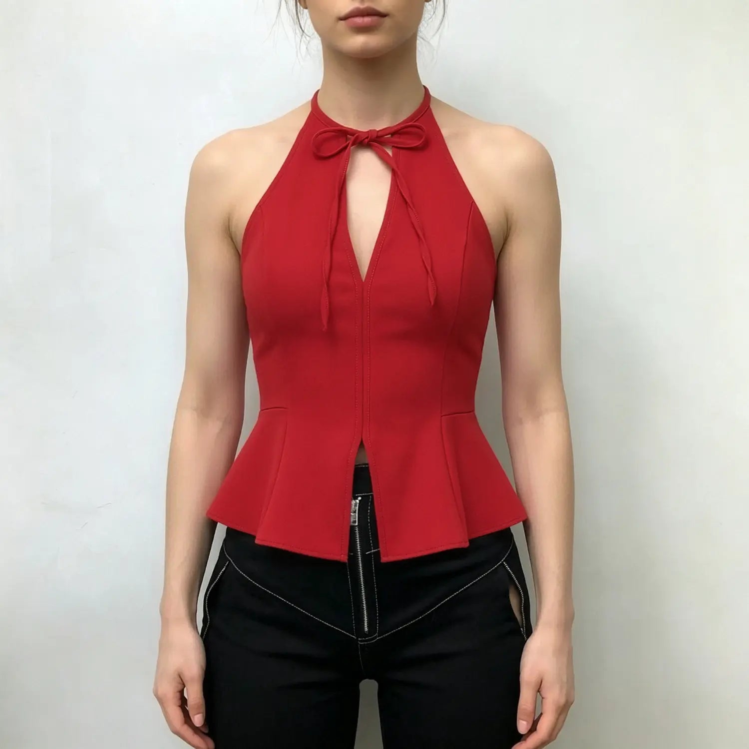 Model wearing red halter peplum top, front tie‑bow keyhole cutout, fitted bodice with flared split peplum hem