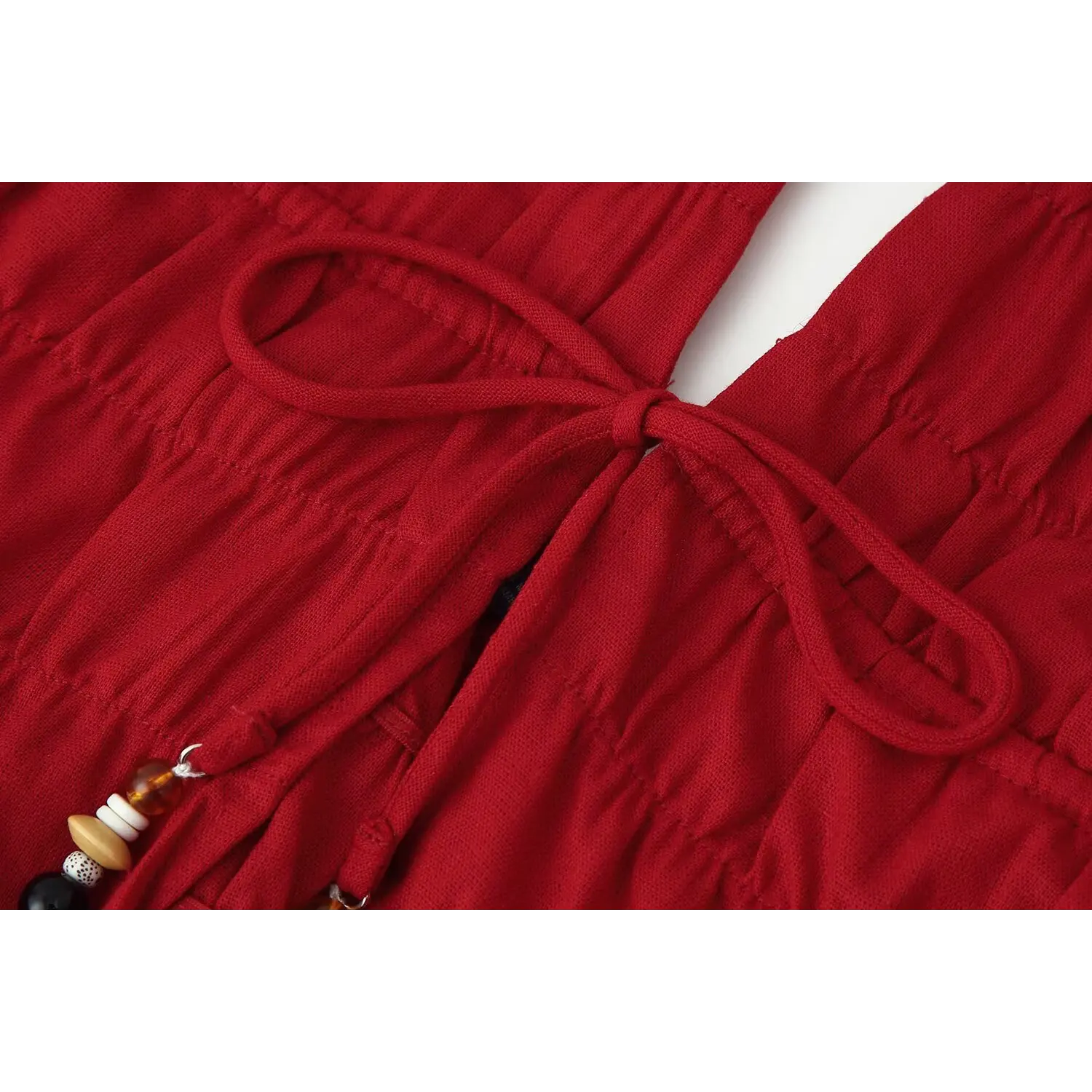 Close‑up detail of red halter top front beaded drawstring tie, ruched fabric texture