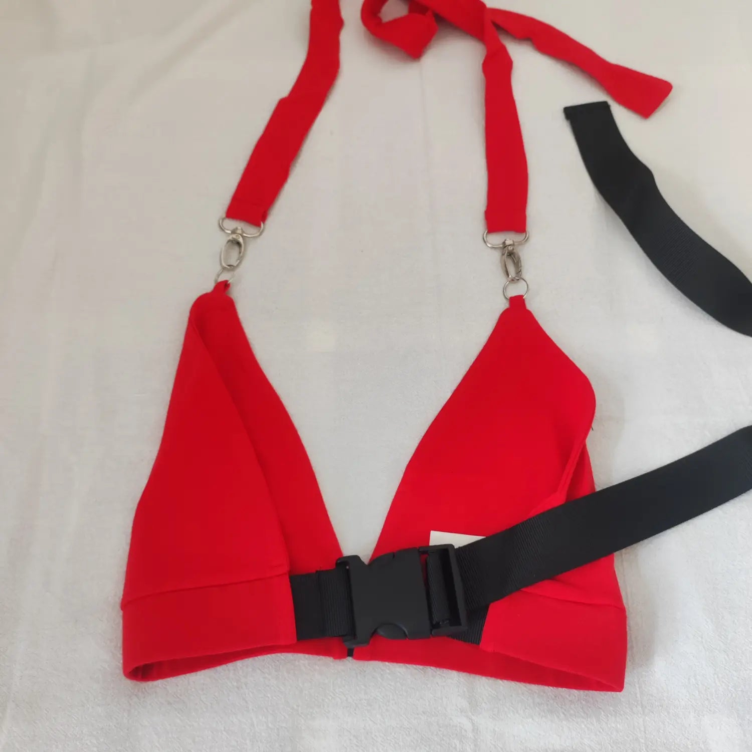 Flat lay front view red halter triangle crop top with black plastic quick release buckle and spare straps