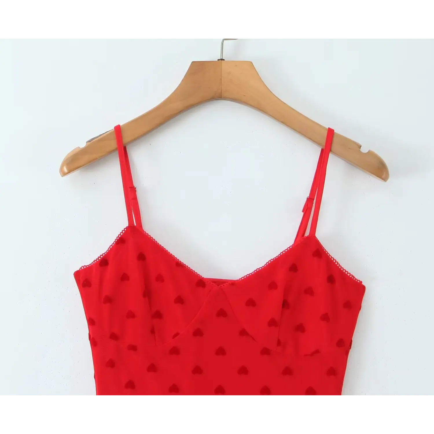 Close‑up v‑neck bodice scallop edge detail red flocked heart mesh cami dress on wooden hanger