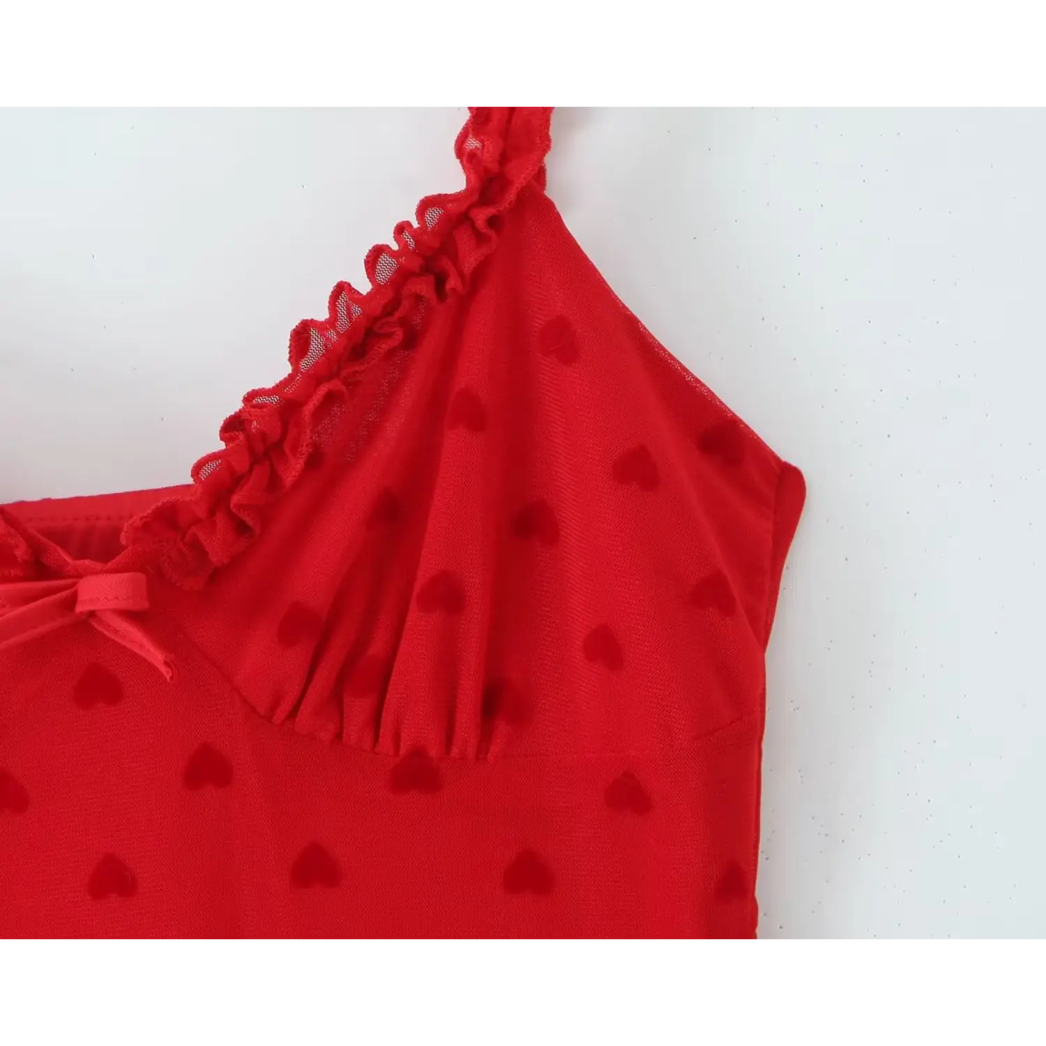 Extreme close‑up fabric texture flocked heart print and ruffle strap detail red mesh cami dress