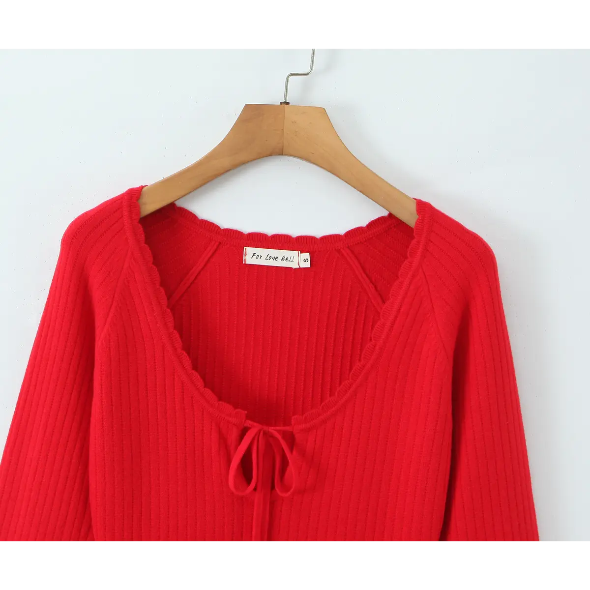 Close-up front view of the U-neckline and tie detail on the red knit dress.