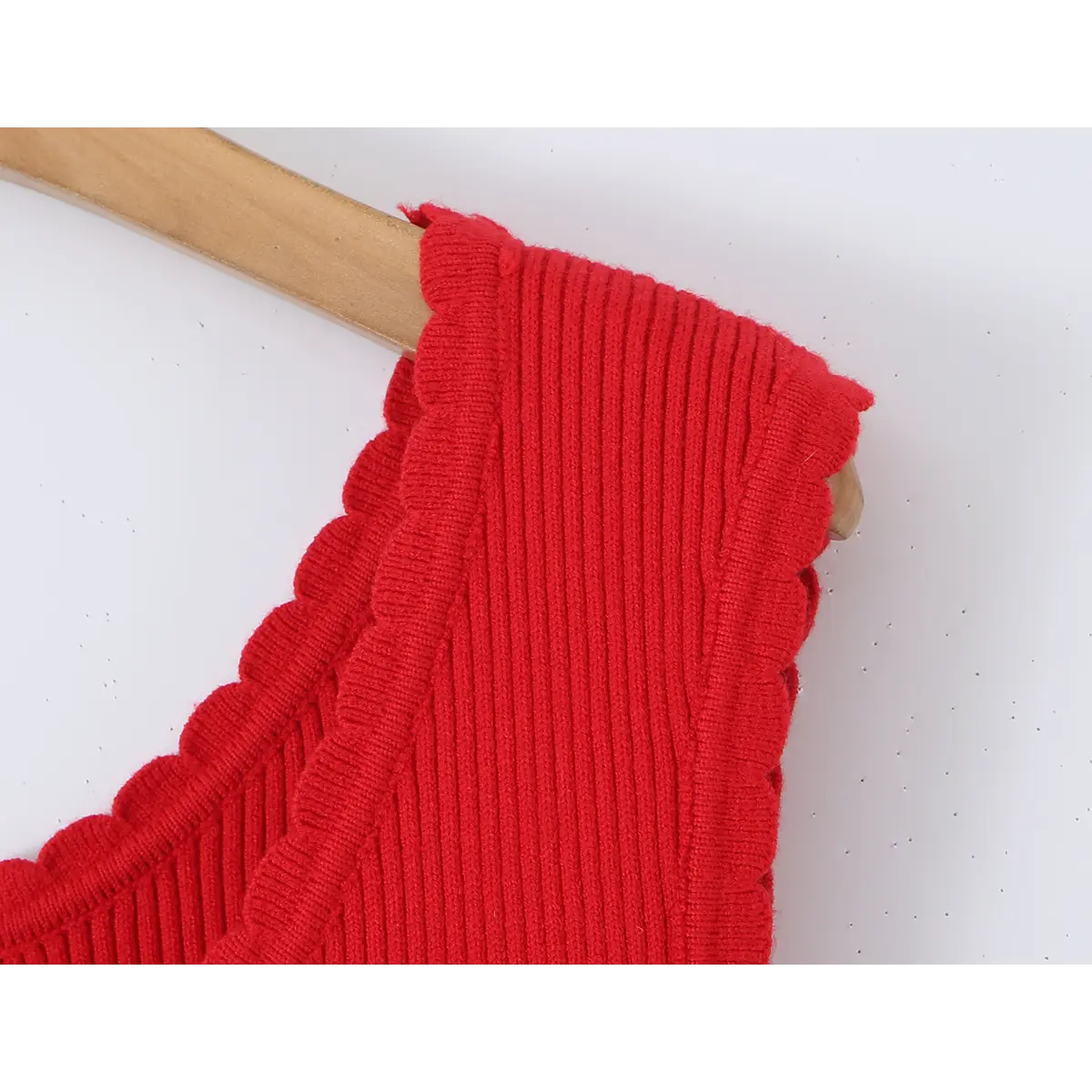 Close-up of the scalloped cap sleeve on a red knit dress, showing the ribbed knit construction.