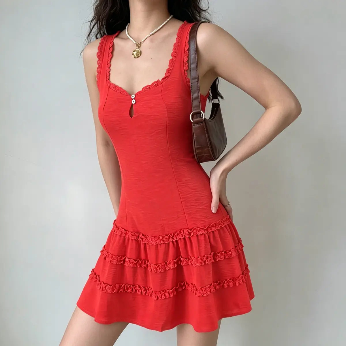Three-quarter view of a model in a red lace-trim tiered mini dress, posing with one hand on her hip.
